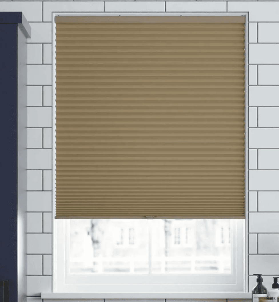 Tan cellular shade on a window with white tile surround.